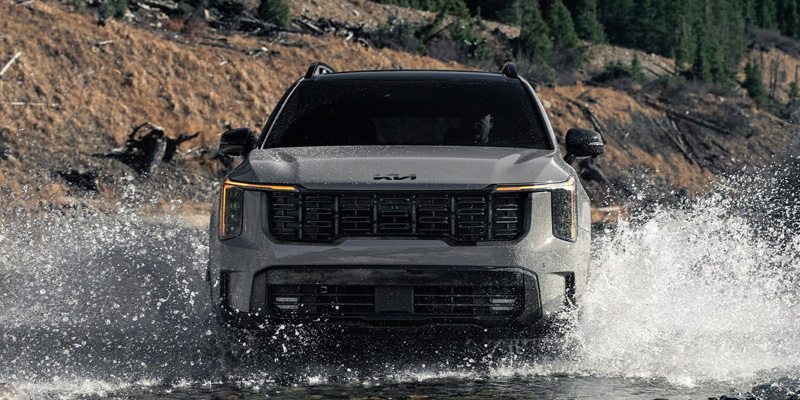 2026 Kia Sorento driving through water in rugged terrain.