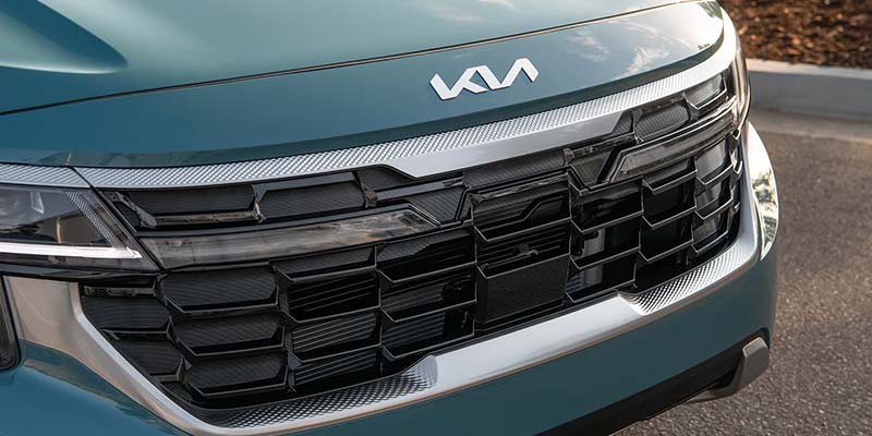 Close-up of the front grille of a Kia vehicle, featuring the brand logo.