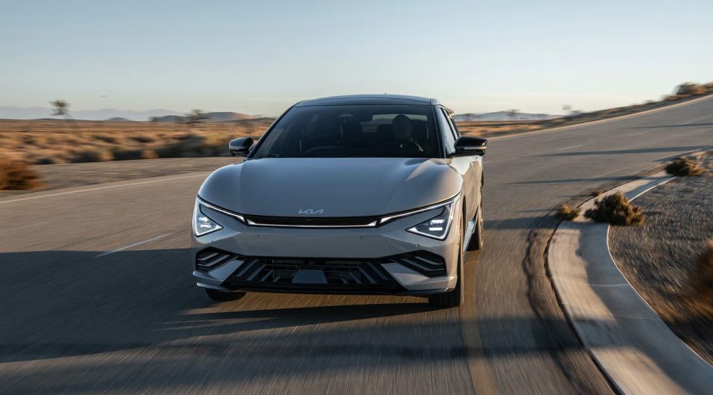 Blue 2026 Kia EV6 electric vehicle driving on a desert road, shown from the front.